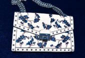 Bolso bandolera blanco con bordado floral azul y cadena plateada