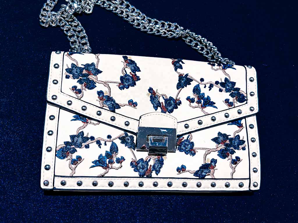 Bolso bandolera blanco con bordado floral azul y cadena plateada