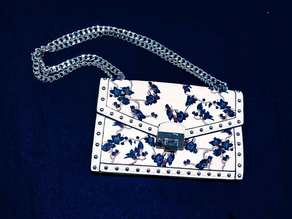 Bolso bandolera blanco con bordado floral azul y cadena plateada