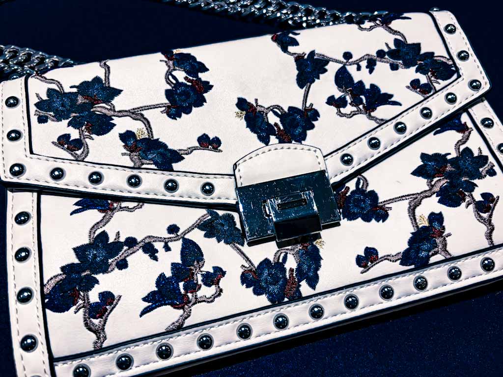 Bolso bandolera blanco con bordado floral azul y cadena plateada
